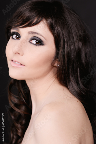 Smiling beautiful woman 20-25 year old with curly hair at black background. Lookng at camera. Young adults. 20s.