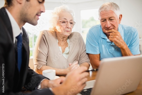 Businessman showing laptop to senior couple
