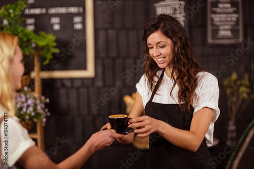 Pretty waitress offering cup of coffee to customer