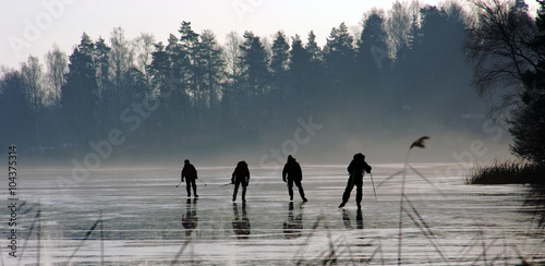 4 personer åker långfärdsskridskor på en sjö photo