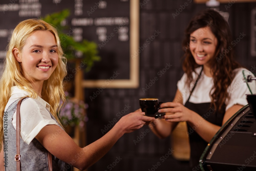 Pretty waitress giving cup of coffee to customer