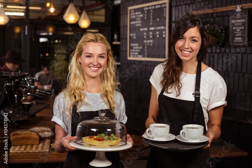 Pretty waitresses posing in front of the counter presenting coffee and pie at the coffee shop