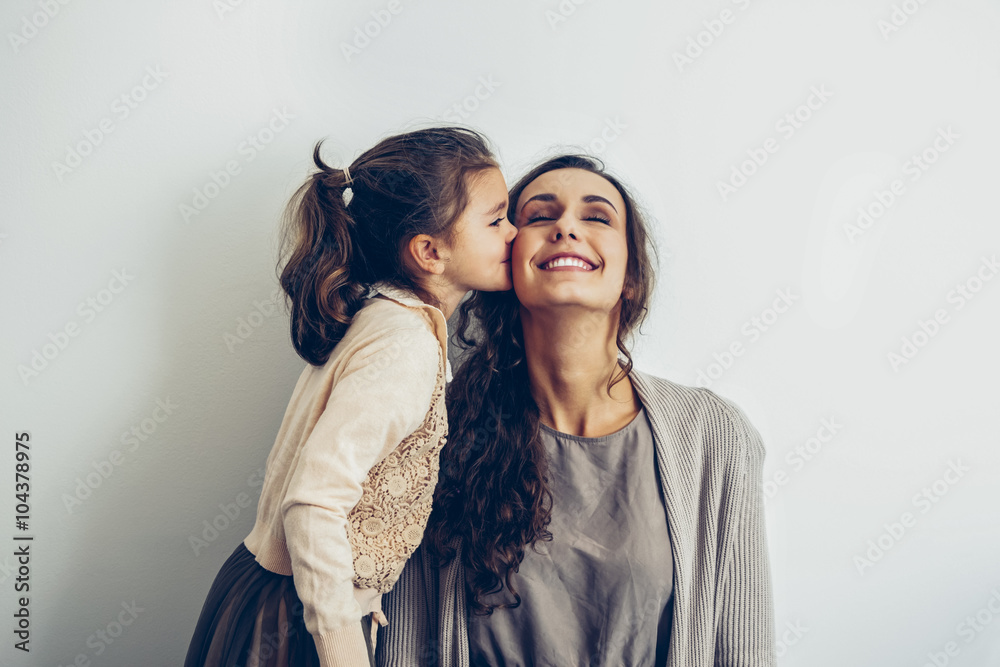 Daughter kissing smiling mother's cheek Daughter kissing smiling mother's cheek