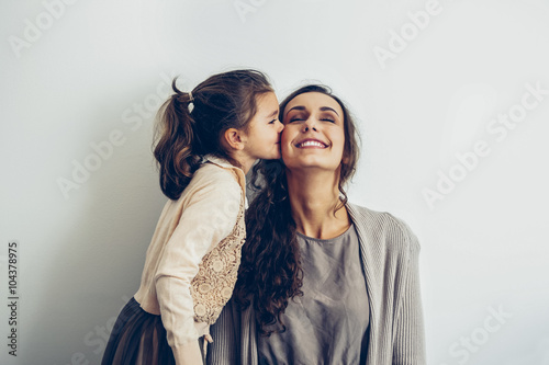 Daughter kissing smiling mother's cheek photo