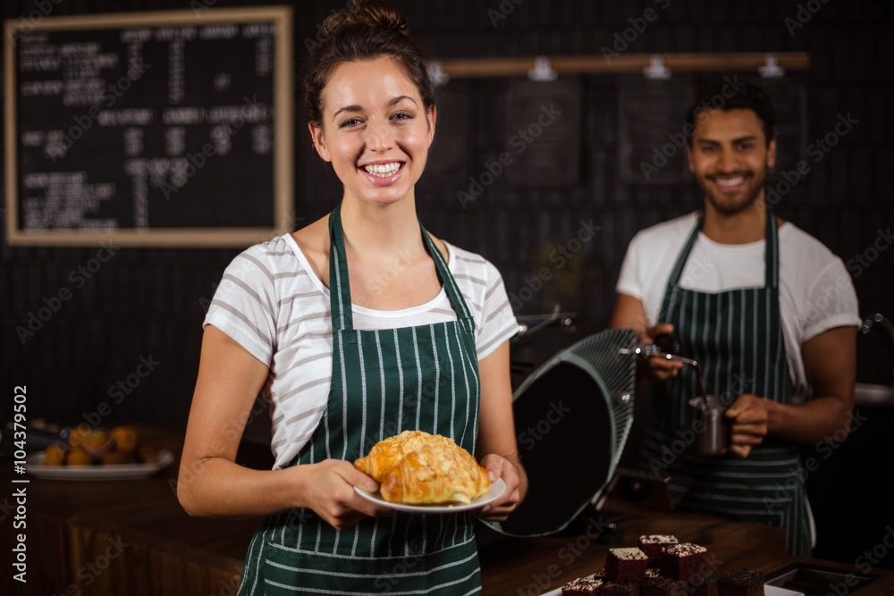 Smiling barista holding croissants