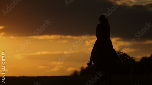 Young woman riding horse into bright sunset. Beautiful Young woman riding horse into amazing sunset