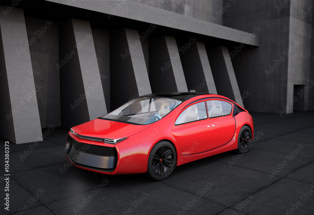 Red electric car in front of geometric object background.