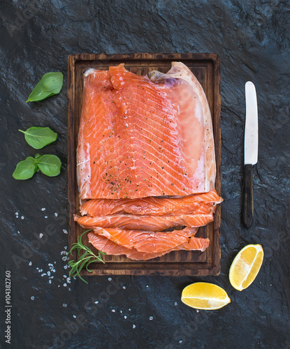 Quadro su tela Smoked salmon filet with lemon, fresh herbs and bred on wooden serving board ove