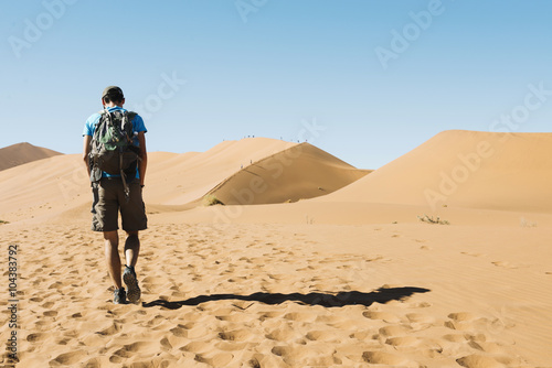 Namibia, Namib Desert, man with backpack walking through the dunes