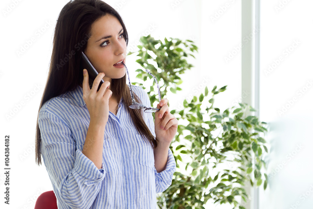 Business young woman using her mobile phone in the office. Business young woman using her mobile phone in the office.