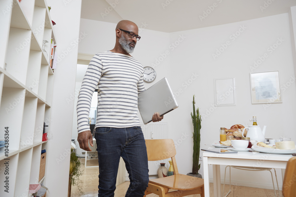 Man with laptop in his kitchen at home Man with laptop in his kitchen at home
