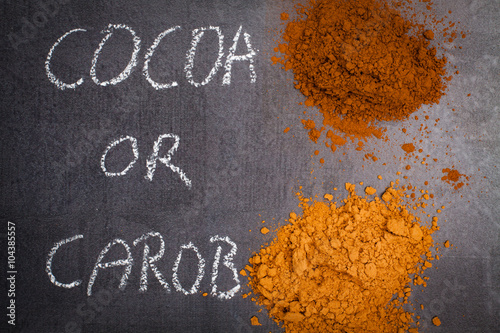 Cocoa and carob powder heap, chalk signed on blck stone background. photo