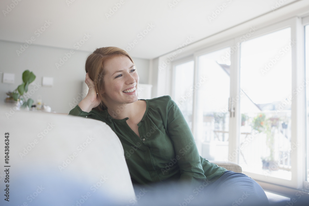 Portrait of smiling young woman sitting on the couch at home Portrait of smiling young woman sitting on the couch at home