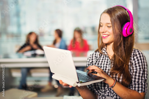 Young woman with laptop standing in interiors of cafe