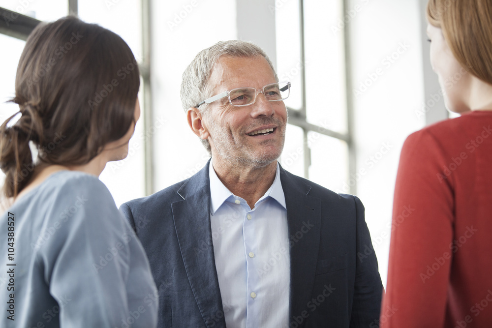 Smiling businessman and two women talking at the window Smiling businessman and two women talking at the window
