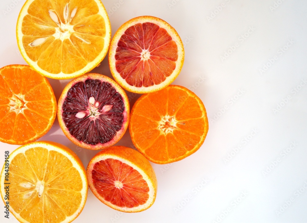 Ruby red blood oranges, navel oranges, and clementines cut in half on a white platter