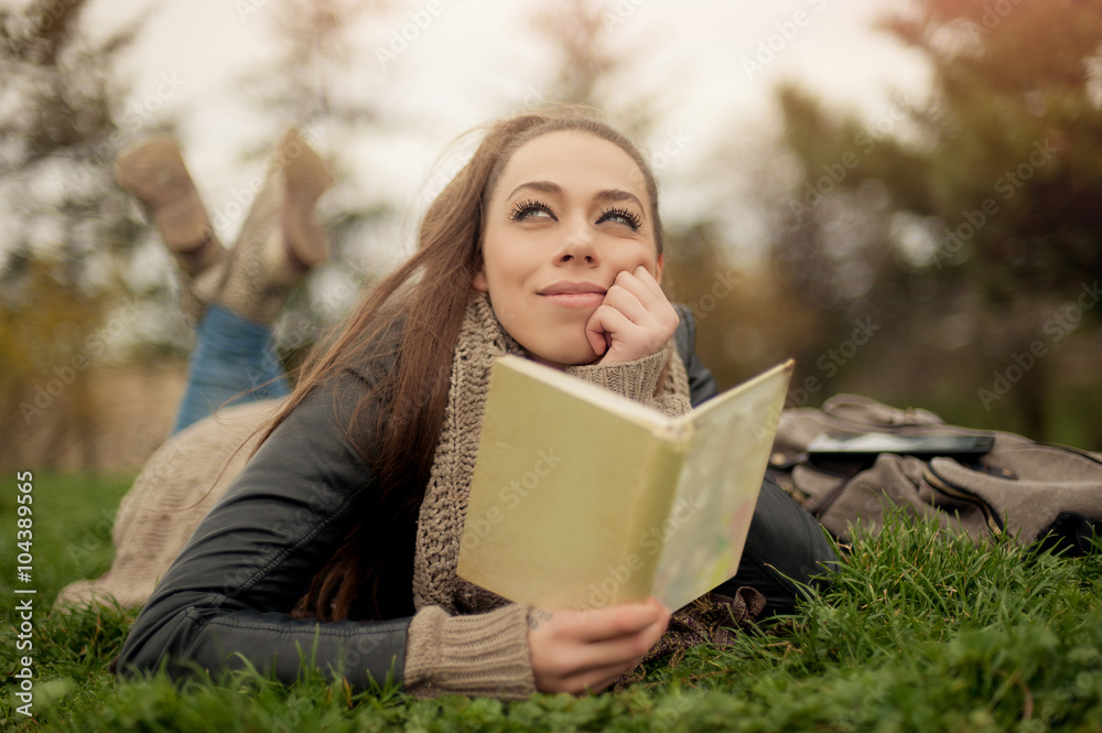Obraz premium Young woman reading book / Closeup of a beautiful young woman reading book at park