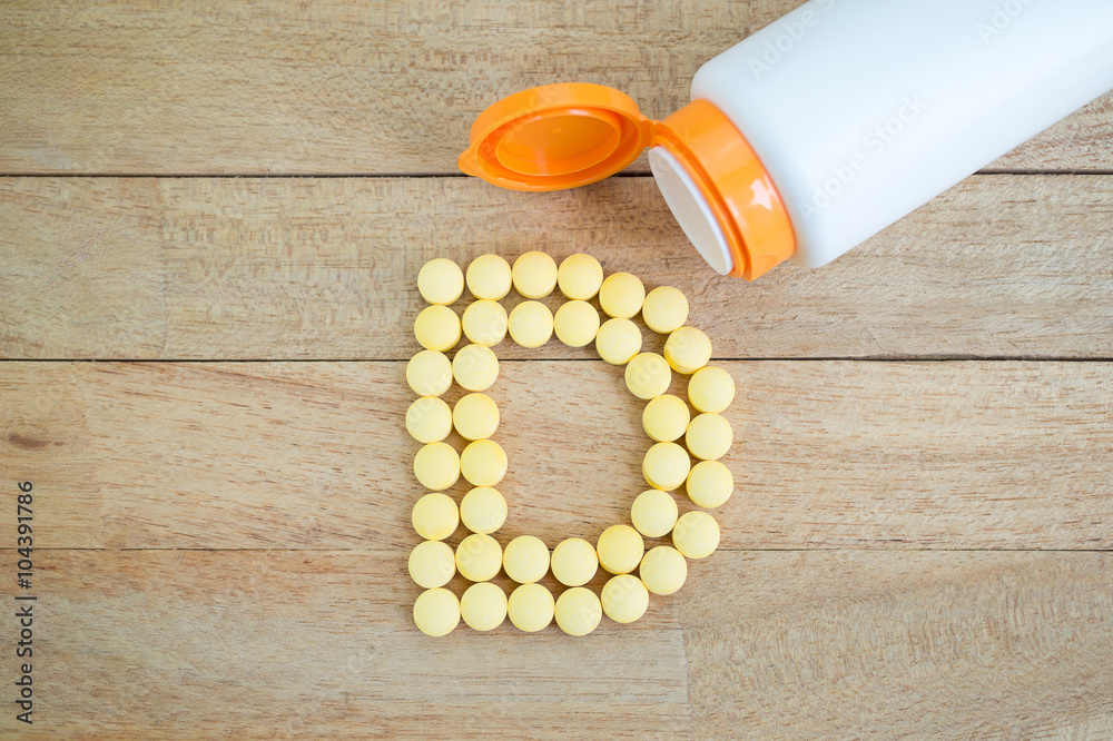 Obraz na płótnie Yellow pills forming shape to D alphabet on wood background w salonie