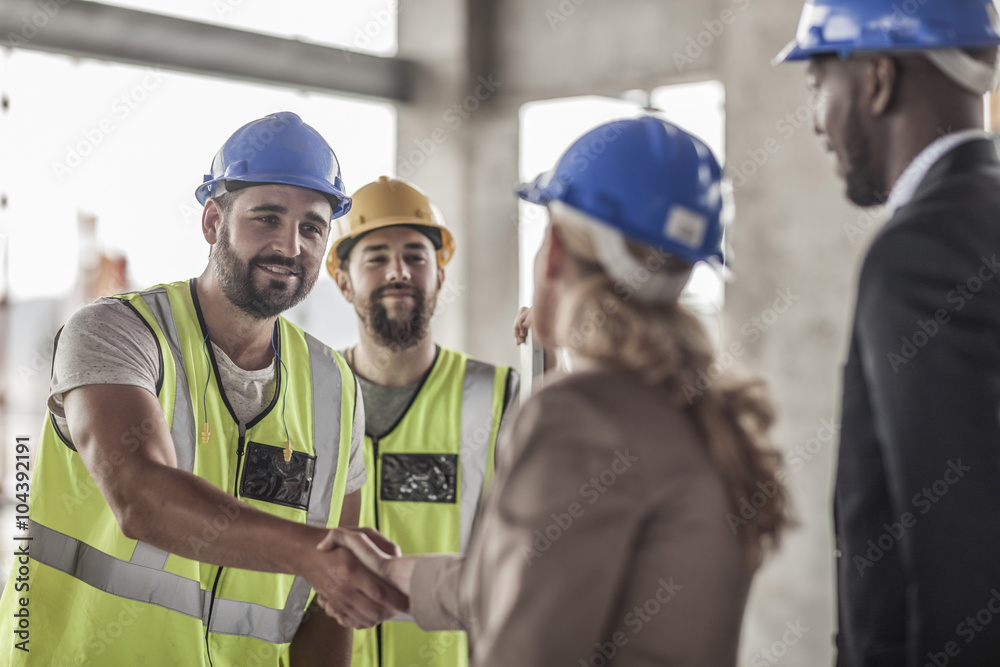 Construction worker and executive shaking hands in construction site