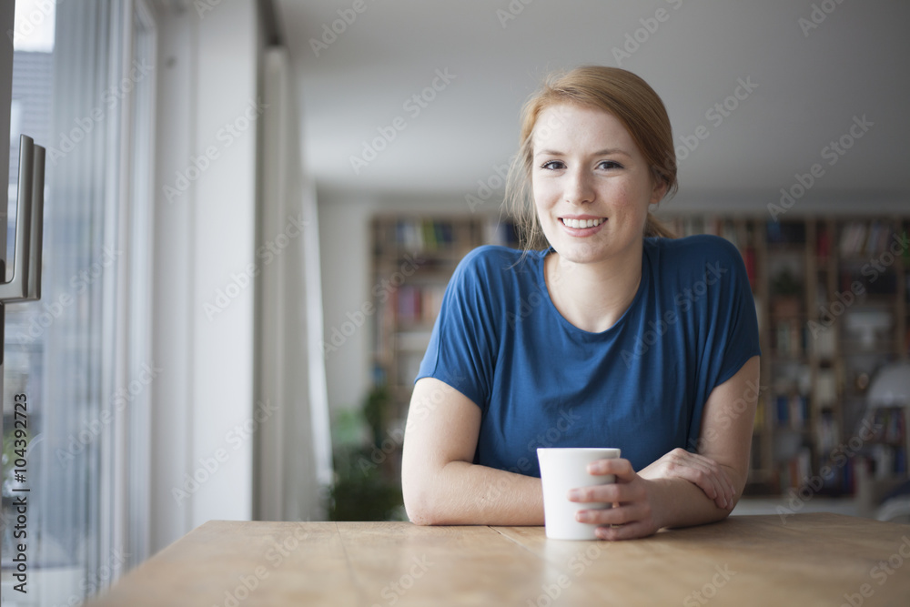 Portrait of smiling young woman sitting at table with cup of coffee Portrait of smiling young woman sitting at table with cup of coffee