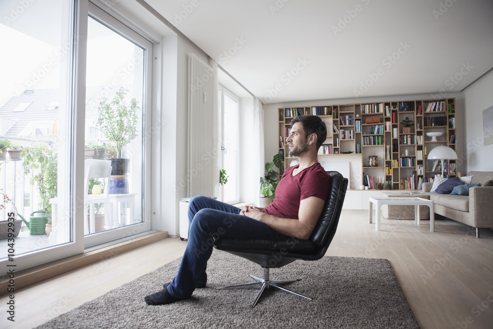 Man at home sitting in armchair looking out of window Man at home sitting in armchair looking out of window