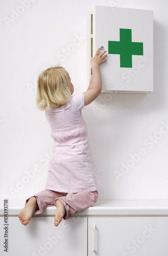 Blond little girl opening medicine cabinet