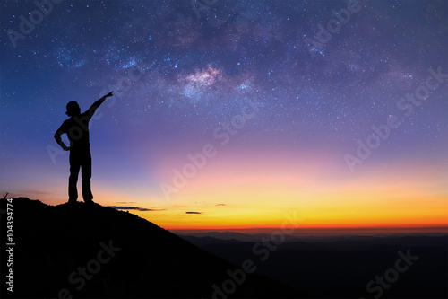 Silhouette of woman is standing on top of mountain and pointing