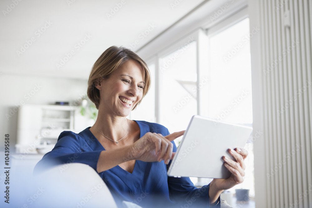 Smiling woman at home sitting on couch using digital tablet Smiling woman at home sitting on couch using digital tablet