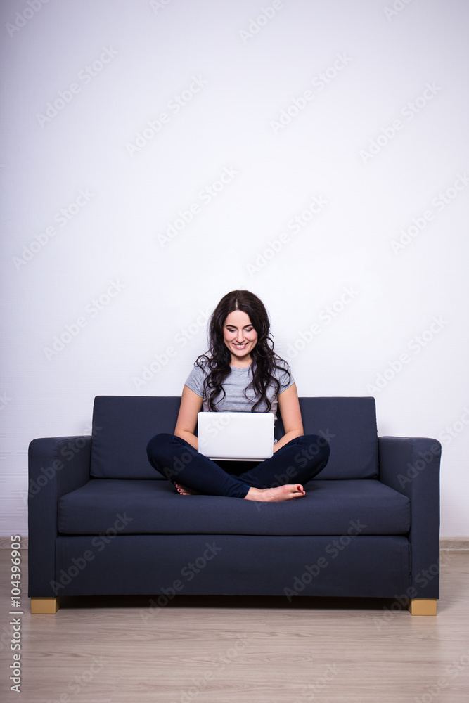 young woman sitting on sofa and using laptop at home