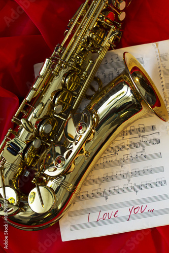 gold saxophone and sheets with notes on a red background