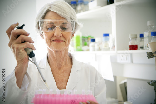 Female professor filling sample glasses in laboratory photo