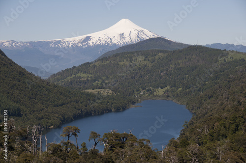 Lago y selva entre montañas con volcán Villarica nevado. Parque Nacional de Huerquehue, Chile photo