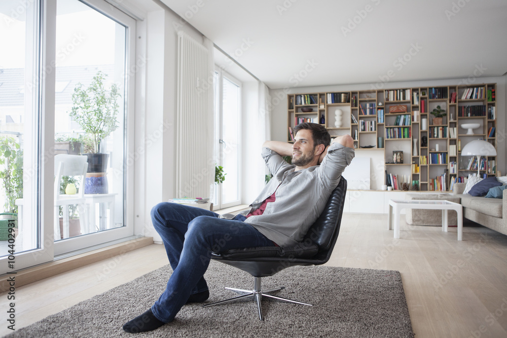 Smiling man at home sitting in armchair with hands behind head Smiling man at home sitting in armchair with hands behind head