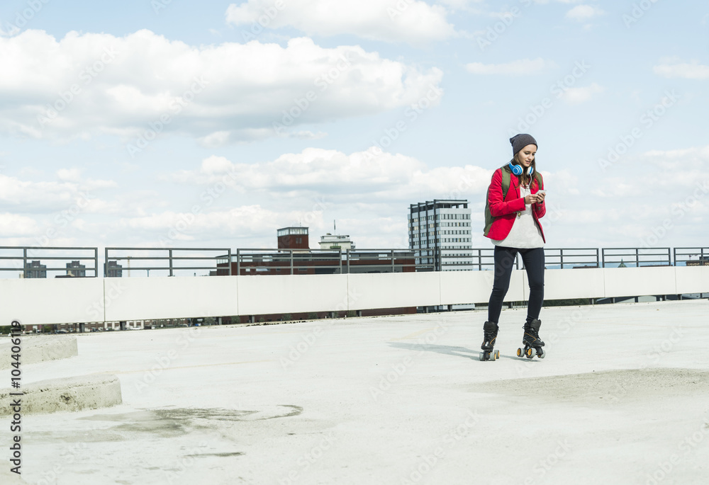 Young woman with cell phone and inline skates on parking level Young woman with cell phone and inline skates on parking level