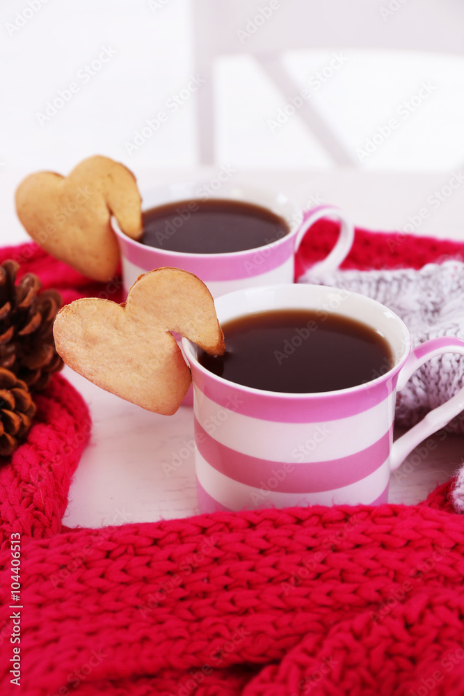 Heart shape cookie on cup of coffee with red knitted scarf closeup Heart shape cookie on cup of coffee with red knitted scarf closeup