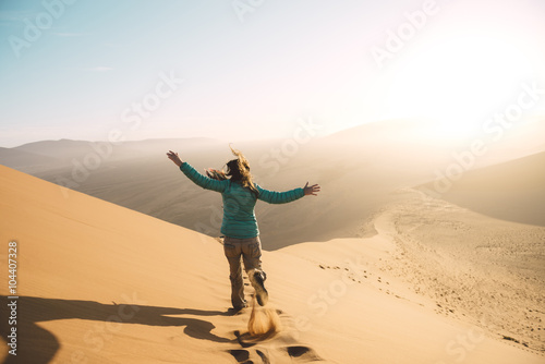 Namibia, Namib Desert, Sossusvlei, Woman running down the Dune at sunrise photo