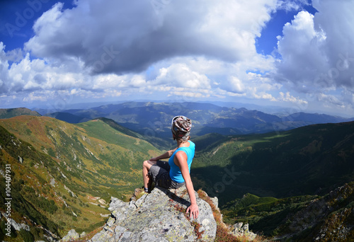 Young woman sitting on a stone in mountains, Carpathian ,Ukraine 