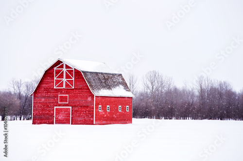 Print op canvas Bright red barn with a hayloft in white winter landscape