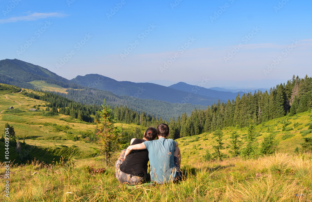 Image of people who are sitting on grass while looking far on the landscape