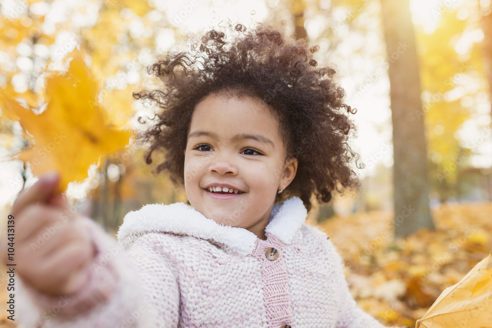 Little girl playing in autumn park