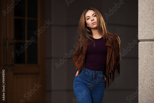 Young fashion woman in red leather jacket walking on city street