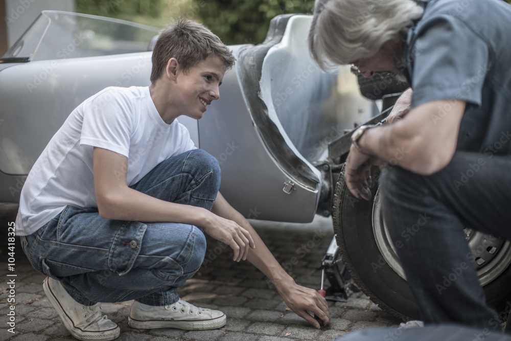 Grandfather and grandson restoring a car together Grandfather and grandson restoring a car together