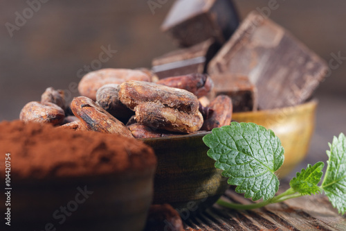 Dark chocolate pieces, cocoa powder and cocoa beans on a wooden table