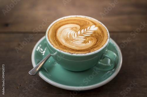 hot cappuccino with latte art on wood background