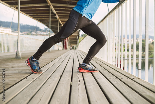 Spain, Naron, legs of a jogger stretching on a wooden bridge photo