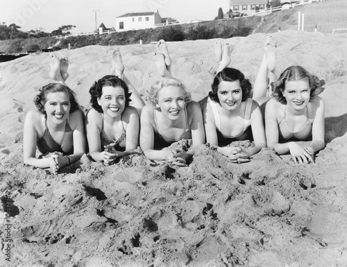 Portrait of five young women lying on the beach and smiling  photo