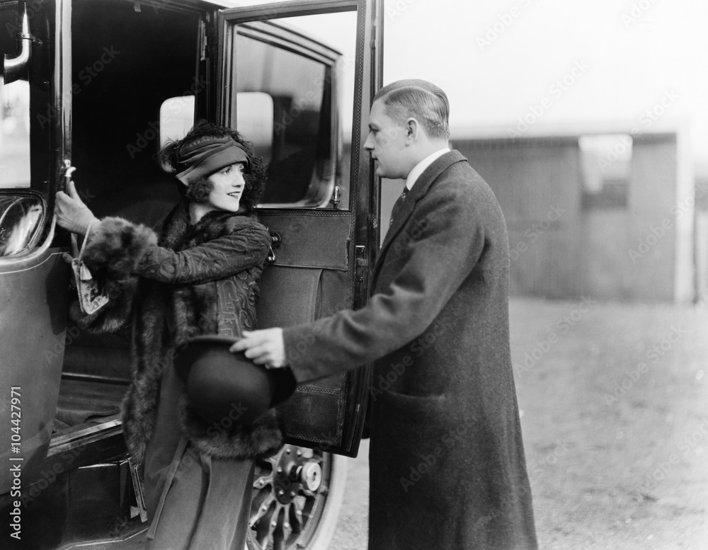 Profile of a man helping a young woman board a car Profile of a man helping a young woman board a car