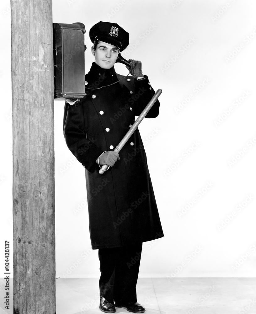 Police officer holding a nightstick and talking on a phone Police officer holding a nightstick and talking on a phone