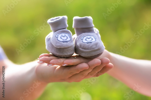 father and mother hold in their hands baby shoes