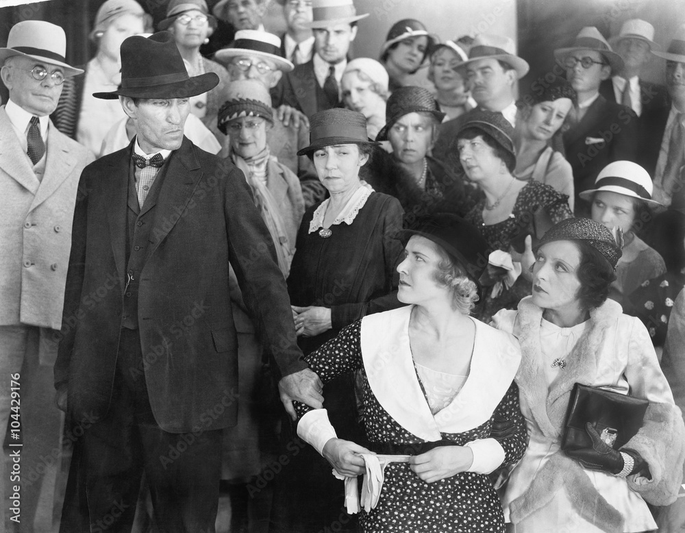 Man looking at his wife in anger while a group of people is watching Man looking at his wife in anger while a group of people is watching